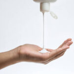 Woman pouring body care lotion from bottle into her hand